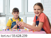 Одна девочка весело смеется, другая корчит рожицы, дети играют в настольную игру. Стоковое фото, фотограф Иванов Алексей / Фотобанк Лори