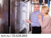 Smiling mature married couple choose for themselves refrigerator. Стоковое фото, фотограф Яков Филимонов / Фотобанк Лори