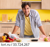 Young man calculating expences for vegetables in kitchen. Стоковое фото, фотограф Elnur / Фотобанк Лори