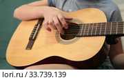 Children hand pluck the strings and fretboard of a yellow acoustic guitar, close up view (2020 год). Редакционное видео, видеограф Кекяляйнен Андрей / Фотобанк Лори
