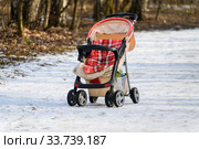An empty baby stroller on the path in the winter Park. Стоковое фото, фотограф Artem Sobov / Фотобанк Лори