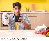 Young man calculating expences for vegetables in kitchen. Стоковое фото, фотограф Elnur / Фотобанк Лори