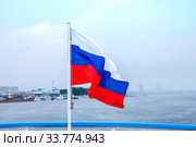Russia, Blagoveshchensk, July 2019: Tricolor flag of Russia on the background of the Amur river near the city of Blagoveshchensk. Редакционное фото, фотограф Катерина Белякина / Фотобанк Лори