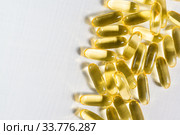 Прозрачные желатиновые овальные капсулы с рыбным жиром лежат на столе. Омега-3 полиненасыщенные жирные кислоты. Место для текста. Стоковое фото, фотограф Наталья Гармашева / Фотобанк Лори