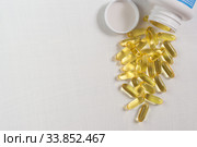 Прозрачные желатиновые овальные капсулы  на белом столе. Омега-3 полиненасыщенные жирные кислоты. Место для текста. Стоковое фото, фотограф Наталья Гармашева / Фотобанк Лори