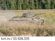 Советский старый средний танк времен Великой Отечественной войны Т-34-76 движется по полю в пыли на ретроралли "Моторы войны", вид сбоку (2018 год). Редакционное фото, фотограф Малышев Андрей / Фотобанк Лори