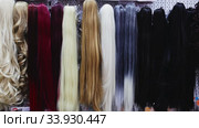 Variety of natural wigs and hairpieces hanging on stand in specialized store. Стоковое видео, видеограф Яков Филимонов / Фотобанк Лори