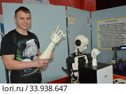 Подросток на выставке интерактивных роботов Robostars держит руку робота (2019 год). Редакционное фото, фотограф Мария / Фотобанк Лори