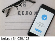 Приложение для смартфона Telegram Messenger (изображение на экране телефона) на папке дело № с очками (2020 год). Редакционное фото, фотограф Кузнецов Максим / Фотобанк Лори
