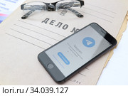 Приложение для смартфона Telegram Messenger (изображение на экране телефона) на папке дело№ с очками (2020 год). Редакционное фото, фотограф Кузнецов Максим / Фотобанк Лори