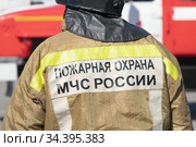 Close-up back view of inscription Emercom of Russia on uniform firefighter of Ministry of Civil Defence, Emergencies and Disaster Relief of Russian Federation MChS (2019 год). Редакционное фото, фотограф А. А. Пирагис / Фотобанк Лори