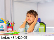 Sad Boy with autism during lesson close ears. Стоковое фото, фотограф Сергей Новиков / Фотобанк Лори