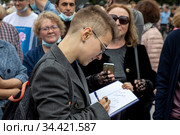 Поэтесса Юлия Мамочева подписывает книгу своих стихов на Пушкинской площади в центре города Москвы, Россия (2020 год). Редакционное фото, фотограф Николай Винокуров / Фотобанк Лори