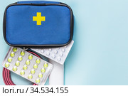 First aid kit on blue background with copy space, medications, pain relievers, antibiotics, vitamins, antidepressants, antivirals, tourniquet for stopping bleeding, bandage for assisting in accidents. Стоковое фото, фотограф Светлана Евграфова / Фотобанк Лори