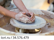 Hands of young potter, creating an earthen jar on the circle, close-up. Стоковое фото, фотограф Nataliia Zhekova / Фотобанк Лори