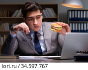 Businessman late at night eating a burger. Стоковое фото, фотограф Elnur / Фотобанк Лори