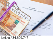 На договоре купли продажи земельного участка лежит пачка денег в продуктовой корзине и шариковая ручка. Стоковое фото, фотограф Иванов Алексей / Фотобанк Лори
