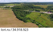 Federal road passing through the agricultural fields, woods in middle part of Russia. Aerial view. Стоковое видео, видеограф Кекяляйнен Андрей / Фотобанк Лори