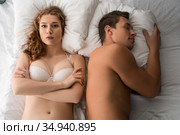 Unsatisfied woman in lingerie lying on bed with sleeping man. Стоковое фото, фотограф Гурьянов Андрей / Фотобанк Лори