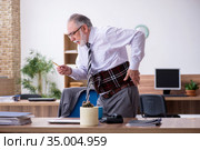 Old male employee suffering from radiculitis at workplace. Стоковое фото, фотограф Elnur / Фотобанк Лори