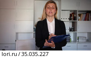 Young adult female assistant standing with clipboard and making notes in modern office. Стоковое видео, видеограф Яков Филимонов / Фотобанк Лори