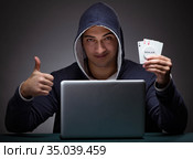 Young man wearing a hoodie sitting in front of a laptop computer. Стоковое фото, фотограф Elnur / Фотобанк Лори