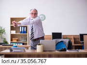 Old male employee suffering from radiculitis at workplace. Стоковое фото, фотограф Elnur / Фотобанк Лори