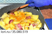A woman with a wooden spoon interferes with the frowning potatoes in a frying pan. Стоковое фото, фотограф Жигалин Михаил / Фотобанк Лори