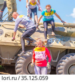 Russia, Samara, June 2019: young athletic people, participants in the hero race, climb through an armored personnel carrier in the village of Roshchinsky near Samara. Text in Russian: race of heroes, platoon. Редакционное фото, фотограф Акиньшин Владимир / Фотобанк Лори