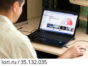 Russia Samara July 2020: A young man during the coronavirus epidemic watches YouTube music on a laptop at night. Редакционное фото, фотограф Акиньшин Владимир / Фотобанк Лори