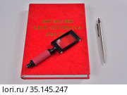 На столе лежат красные офисные предметы: степлер, дырокол, блокнот, лупа, справочник и авторучка. Стоковое фото, фотограф Максим Мицун / Фотобанк Лори