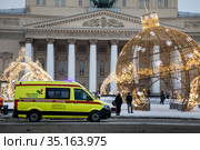 Автомобиль скорой медицинской помощи едет по улице в центре города Москвы на фоне фасада Большого театра в канун Нового года, Россия (2020 год). Редакционное фото, фотограф Николай Винокуров / Фотобанк Лори