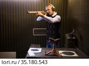 Focused man aiming shotgun at target in shooting range. Стоковое фото, фотограф Яков Филимонов / Фотобанк Лори