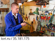 Confident gunsmith lubricates and cleans barrel of rifled shotgun. Стоковое фото, фотограф Яков Филимонов / Фотобанк Лори