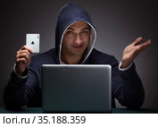 Young man wearing a hoodie sitting in front of a laptop computer. Стоковое фото, фотограф Elnur / Фотобанк Лори