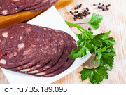 Close up of Spanish smoked blood sausage on white plate on wooden table. Стоковое фото, фотограф Яков Филимонов / Фотобанк Лори