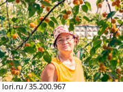 beautiful mature woman stands under an apricot tree on a summer day. Стоковое фото, фотограф Акиньшин Владимир / Фотобанк Лори