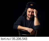Портрет улыбающегося мужчины тридцати лет кавказской внешности в советской офицерской меховой шапке на черном фоне. Стоковое фото, фотограф Иванов Алексей / Фотобанк Лори