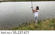 Happy woman with rod catching the small fish in lake, recreational fishing from the shore. Стоковое видео, видеограф Кекяляйнен Андрей / Фотобанк Лори