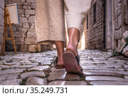 Detail shot of female legs wearing comfortable travel sandals walking on old medieval cobblestones street dring sightseeing city tour. Travel, tourism and adventure concept. Стоковое фото, фотограф Matej Kastelic / Фотобанк Лори