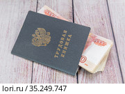 Трудовая книжка и российские деньги на столе. Выплаты по трудовому договору. Стоковое фото, фотограф Наталья Осипова / Фотобанк Лори