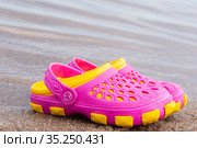 Детские розовые сабо стоят на песчаном пляже около воды. Children's pink clogs stand on a sandy beach near the water. Стоковое фото, фотограф Мария / Фотобанк Лори