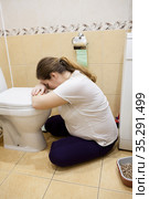 Young Caucasian woman sitting on the floor in toilet. Pregnant, Drunk or illness concept. Стоковое фото, фотограф Кекяляйнен Андрей / Фотобанк Лори
