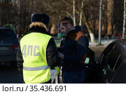 Инспектор дорожно-патрульной службы полиции проверяет документы водителя остановленного автомобиля (2016 год). Редакционное фото, фотограф Free Wind / Фотобанк Лори