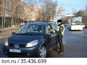 Инспектор дорожно-патрульной службы полиции проверяет документы водителя остановленного автомобиля (2016 год). Редакционное фото, фотограф Free Wind / Фотобанк Лори