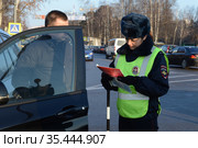 Инспектор дорожно-патрульной службы полиции проверяет документы водителя остановленного автомобиля (2016 год). Редакционное фото, фотограф Free Wind / Фотобанк Лори