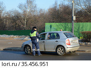 Инспектор дорожно-патрульной службы полиции проверяет документы водителя остановленного автомобиля (2016 год). Редакционное фото, фотограф Free Wind / Фотобанк Лори