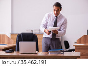 Young male employee stapling paper in the office. Стоковое фото, фотограф Elnur / Фотобанк Лори