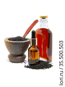 Семена черного тмина (Black cumin) в ступке и масло в бутылках на белом фоне. Стоковое фото, фотограф Татьяна Белова / Фотобанк Лори