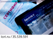 Вид на сертификат о прохождении вакцинации от коронавирусной инфекции COVID-19 и сайт российской вакцины Sputnik V на планшете (2021 год). Редакционное фото, фотограф Николай Винокуров / Фотобанк Лори